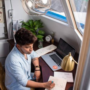 Photo by manny PANTOJA man sits while writing in front of MacBook